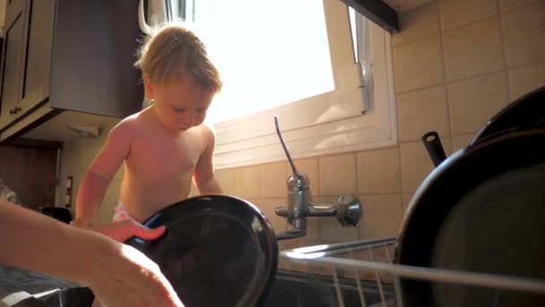 Mom with her 2 years old child washing dish. Cleaning in the kitchen to Mothers day, casual lifestyle photo series in real life interior. 1,4 years old child washing dishes with parent — 图库视频影像