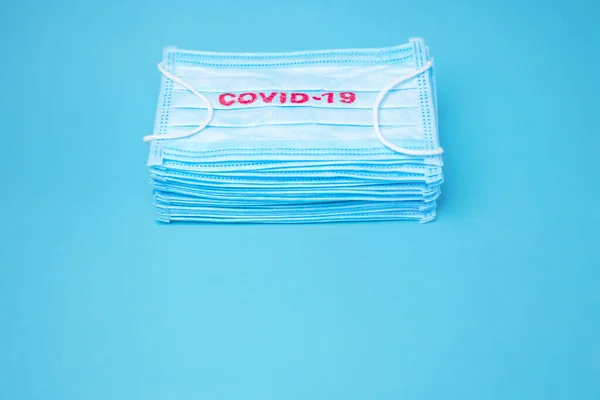 Covid-19 background. Epidemic backround. Facial mask in the pile. Quarantine background. Healthcare background. Blue medical disposable face mask with covid-19 print. Facial mask wholesale, in pile, — Stock Photo, Image