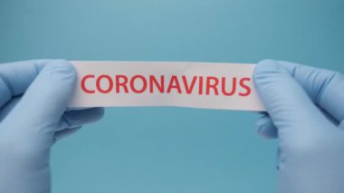 Coronavirus geçmişi. Tıbbi eldivenlerdeki eller üzerinde koronavirüs olan bir kağıt parçası tutuyor. Covid-19 - Wuhan Roman Coronavirus pnömonisi: Tehlikeli virüs, bakteri.