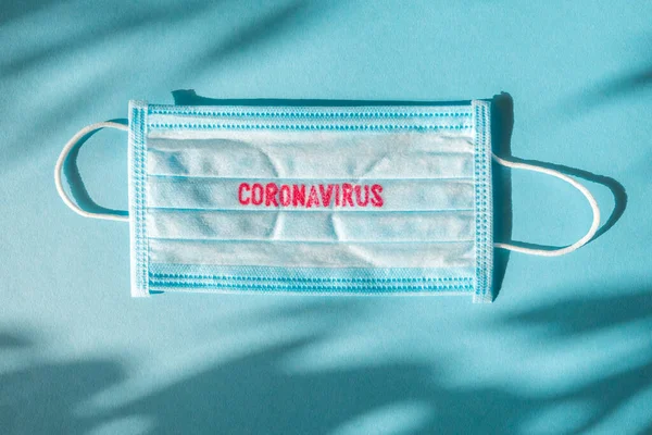 Coronavirus - Wuhan Novel A pneumonia por Coronavirus recebe o nome oficial da OMS: COVID-19. Molho descartável no rosto. Antecedentes de saúde. Máscara facial descartável médica azul com impressão covid-19 — Fotografia de Stock