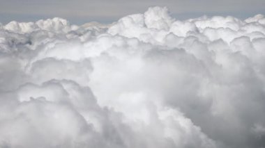 Uçak penceresinden yükselen bulutlu gökyüzü. Bir uçağın penceresinden muhteşem bir manzara. Kabarık kar beyazı bulutların arasında uçar. Bulutların üzerinde uçuyor
