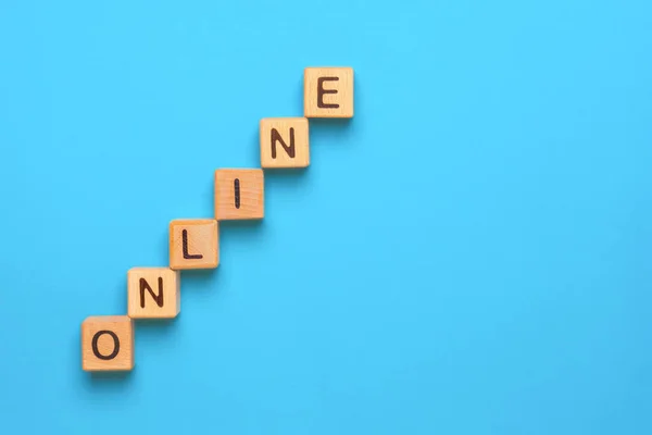 Word Online, mavi arka planda tahta harf baskı küpleriyle yapılmış. Tahta küplere yazılmış ONLINE. Kavramsal. Çevrimiçi iş genişliyor. İşletmeyi genişletiyorum. Gelir kavramını arttır. Evde kal. — Stok fotoğraf