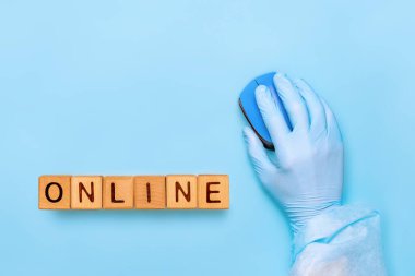 Tahta küplere, bloklara ONLINE yazıldı. Kavramsal. Evde kal. Coronavirus karantina geçmişi. Tıbbi eldiveni bilgisayar faresiyle birlikte ver. Bilgisayar faresi olan koruyucu giyimli bir doktor.