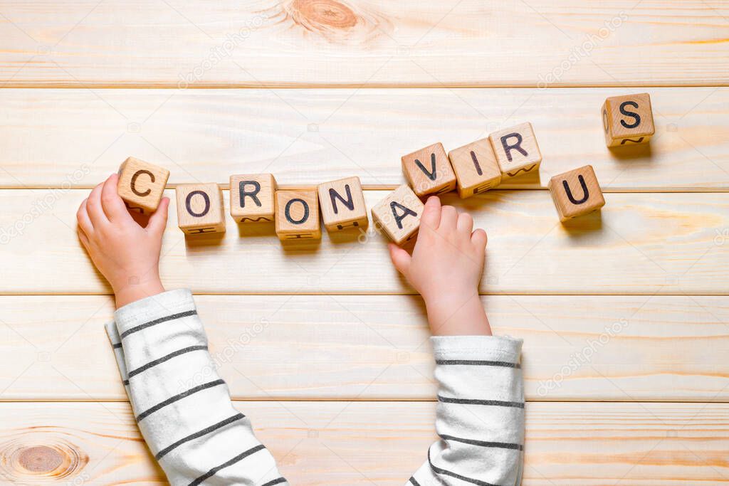 Child lays out word CORONAVIRUS. Coronavirus COVID-19 word made from wooden cubes. SARS-COV-2, Pandemic, epidemic background. Children and epidemic. nCov-2, kids hands laying out word