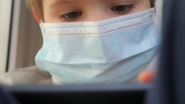 Pencere kenarındaki çocuk oyun oynuyor. E-öğrenim, ev okulu geçmişi. Çocuklar ve teknolojiler. Evde kal. Evde ders çalışıyorum. Karantina uzadı. Sosyal uzaklık. Salgın sırasında çevrimiçi öğrenme