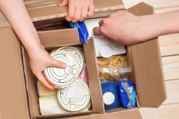 Assistance concept at quarantine time because of coronavirus infection Covid-19. Hands opening a food delivery box at home, online ordering. Grocery store delivery. Box of food in donation boxparcel. — Stock Photo, Image