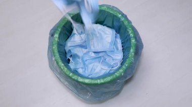 Koruyucu maskeler kullanılmış. Yüz maskesini çöpe atıyorum. Korunma sırasında. Salgının sonu. Karantina süresi bitti. Eldivenler ve mavi çöp torbası. Çevre kirliliği