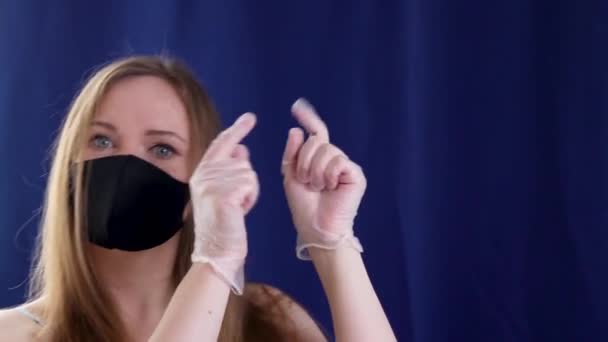 Siyah kumaş maskeli beyaz kız eldivenli parmaklarıyla yönü gösteriyor. — Stok video