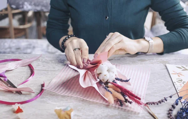 Kadın eli bir buket kurumuş çiçek yapar. Seçici odaklanma. Çiçekçiliğin ustası.