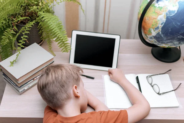 Okul çocuğu masanın üstünde uyuyor. Çalışmaktan yoruldum. Arkadan bak. seçici odak