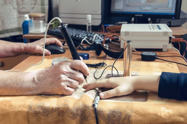 Bir teşhis uzmanının eli, biyoresans yardımıyla bir çocuğun elini muayene eder.