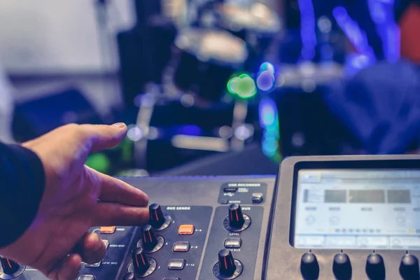 La mano del ingeniero de sonido ajusta el sonido en una consola digital moderna. tambor establecido en el escenario borroso en el fondo — Foto de Stock