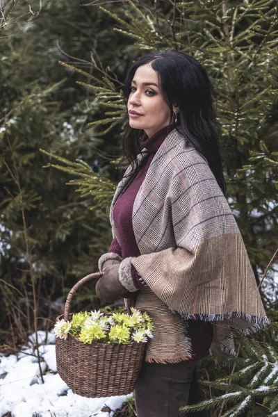 Arka planında bir sepet kardelen olan genç bir kadının portresi.