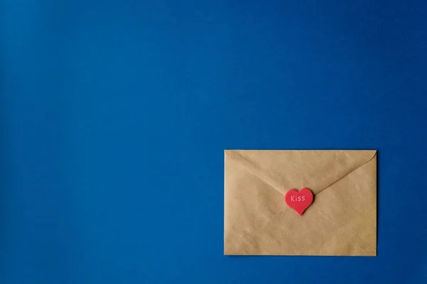 Carta de amor de São Valentim de papel artesanal com coração vermelho com palavra beijo no fundo azul clássico. Horizontal. Cor 2020 . — Fotografia de Stock