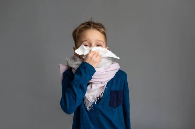 Caucasian 7 year old sick boy blowing his nose. Virus concept.
