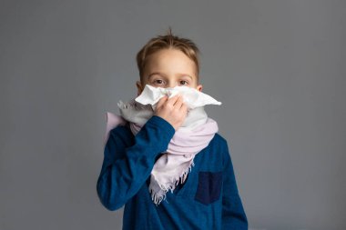 Caucasian 7 year old sick boy blowing his nose. Virus concept.