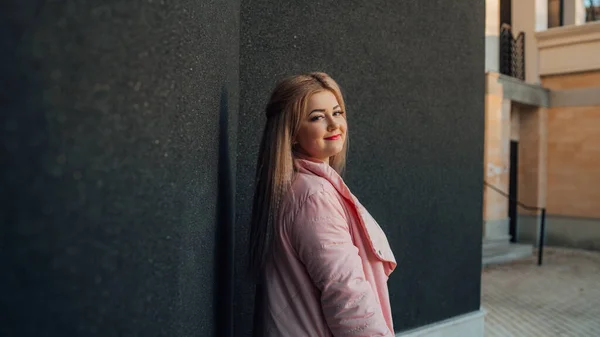 Un retrato de una hermosa chica, posando sobre el fondo de una pared gris . — Foto de Stock