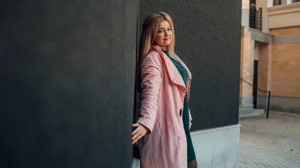 Um retrato de uma menina bonita, posando contra o fundo de uma parede cinza . — Fotografia de Stock