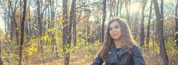 Mulher bonita posando de pé na floresta de outono. Menina em couro jaqueta preta andando na floresta — Fotografia de Stock