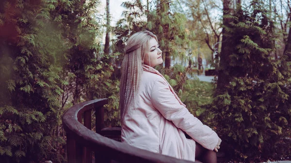 푸른 초목 근처에 있는 긴 의자에 앉아 있는 아름다운 여인의 모습. — 스톡 사진