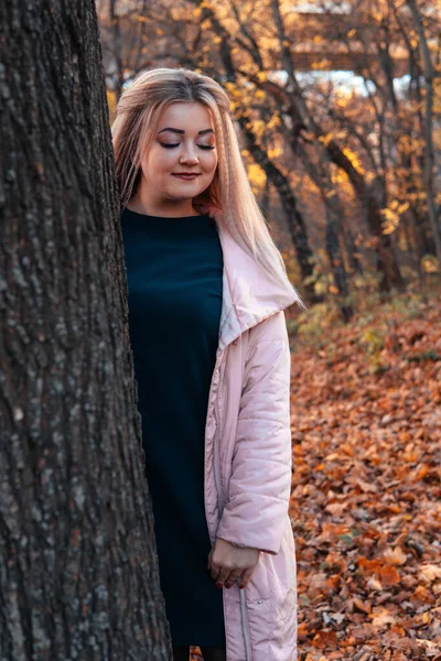 Bella donna che si affaccia da dietro l'albero. Bella donna calma toccando albero e guardando la macchina fotografica in foresta tranquilla — Foto Stock