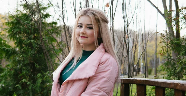 Een portret van een mooie vrouw, zittend op een bankje bij de groene vegetatie. — Stockfoto