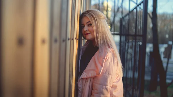 Un ritratto di una bella ragazza, in posa vicino a una recinzione di legno al tramonto in primavera . — Foto Stock