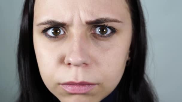 Gyönyörű nő dühös és ráncos, közelről. Egy dühös nő arca gonosz ijesztő szemekkel. — Stock videók