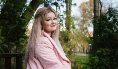 Yeşil bitki örtüsünün yanındaki bankta oturan güzel bir kadının portresi..