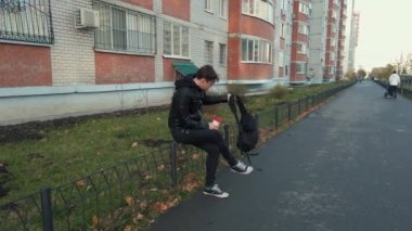 Gündelik giysiler içinde genç yakışıklı bir adam küçük bir çitte oturuyor ve şehir merkezinde bir kahve içiyor..