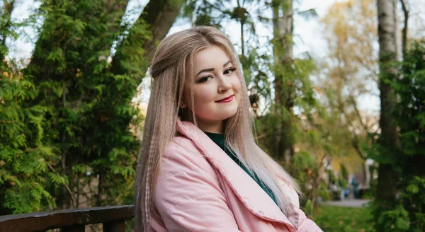 Een portret van een mooie vrouw, zittend op een bankje bij de groene vegetatie. — Stockfoto