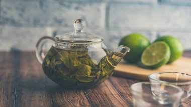 Çay yaprakları kaynayan suda demlenir ve küçük bir çaydanlığa karışır. Çay partisi konsepti. Çaydanlıkta yeşil çay