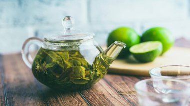 Çay yaprakları kaynayan suda demlenir ve küçük bir çaydanlığa karışır. Çay partisi konsepti. Çaydanlıkta yeşil çay