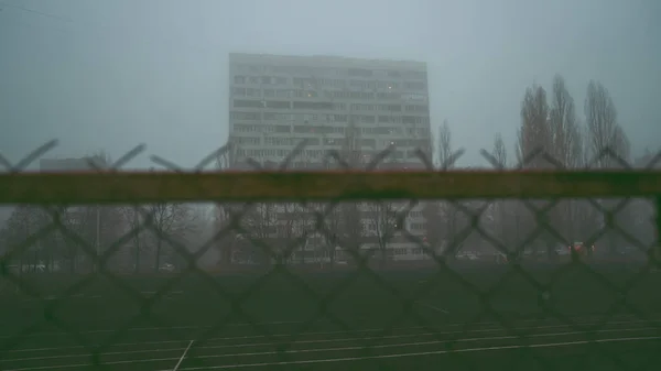 Antecedentes urbanos. Edificio de varios pisos en la mañana, en la niebla. Edificio de apartamentos tras las rejas. Gueto, que alberga a los pobres. Concepto: restricción de la libertad — Foto de Stock