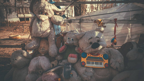 Old and battered soft toys lie on the street. The dump of the abandoned toys