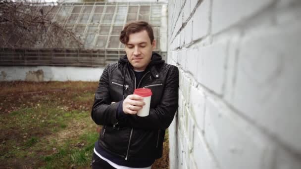 Retrato de un joven guapo con taza de café de pared de ladrillo. Retrato de un joven guapo con taza de café en el fondo de la pared de ladrillo. — Vídeos de Stock