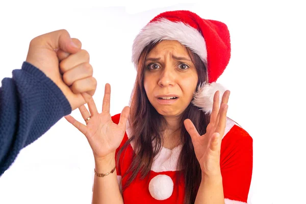 Homem está batendo mulher assustada em terno de Santa Cláusula na cara com punho. Um homem agressivo está batendo jovem mulher assustada com grandes olhos assustados . — Fotografia de Stock