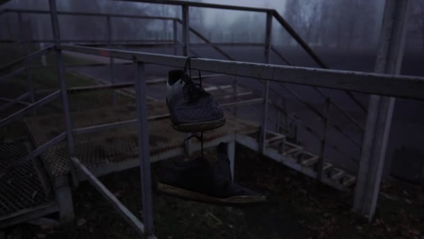 Alte Schuhe hängen an den Schnürsenkeln am Zaun. — Stockvideo