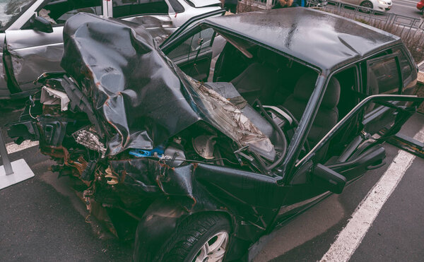 The car after the accident. Broken car on the road. The body of the car is damaged as a result of an accident. High speed head on a car traffic accident. Dents on the car body after a collision on the