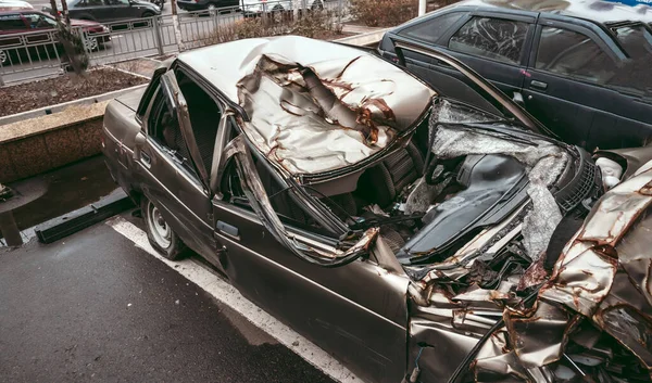 The car after the accident. Broken car on the road. The body of the car is damaged as a result of an accident. High speed head on a car traffic accident. Dents on the car body after a collision on the — Stock Photo, Image