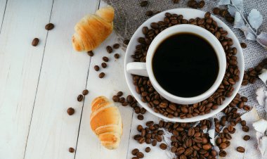 Kahve çekirdekli kahve ve eski ahşap masada kruvasan. Sade kahve ya da americano ile servis edilen ev yapımı kruvasan. Lezzetli kruvasanla kahve molası. Sonbahar kompozisyonu hala hayat.