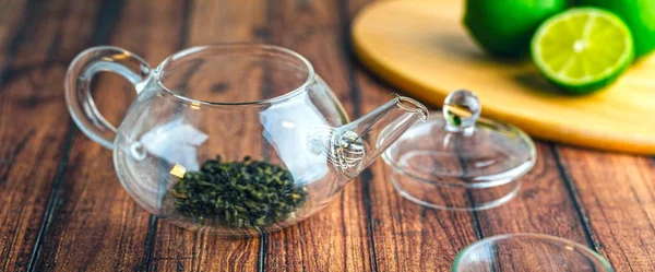 Une théière en verre avec des feuilles de thé à l'intérieur sur une table en bois . — Photo