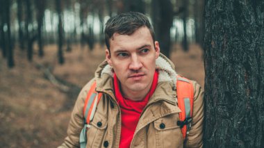 Ormanda haritası olan gezgin bir adam. Soğuk bir havada bir ağacın yanında duran sırt çantalı yakışıklı adamın portresi..