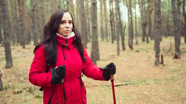 Uma jovem bonita está envolvida na caminhada nórdica na floresta. . — Fotografia de Stock