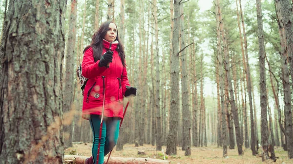 Ładna młoda kobieta jest zaangażowana w nordic walking w lesie. — Zdjęcie stockowe