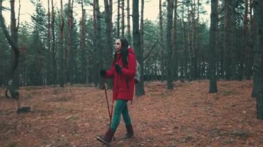 Genç ve güzel bir kadın kuzeyde ağaçların arasında yürüyor..