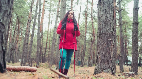 A pretty young woman is engaged in the nordic walking in woods. — Stock Photo, Image