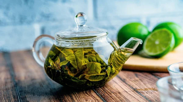 Листья чая варят в кипящей воде и вливают в небольшой чайник. Концепция чайной вечеринки. Зеленый чай в чайнике — стоковое фото