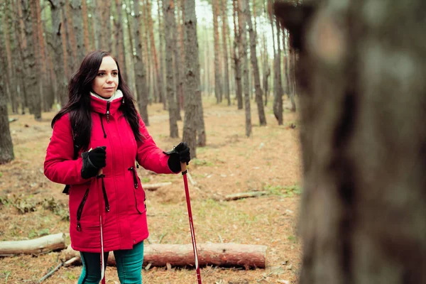 Uma jovem bonita está envolvida na caminhada nórdica na floresta. . — Fotografia de Stock