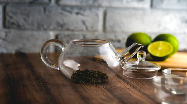 Sebuah teko kaca dengan daun teh di dalam meja kayu . — Stok Foto